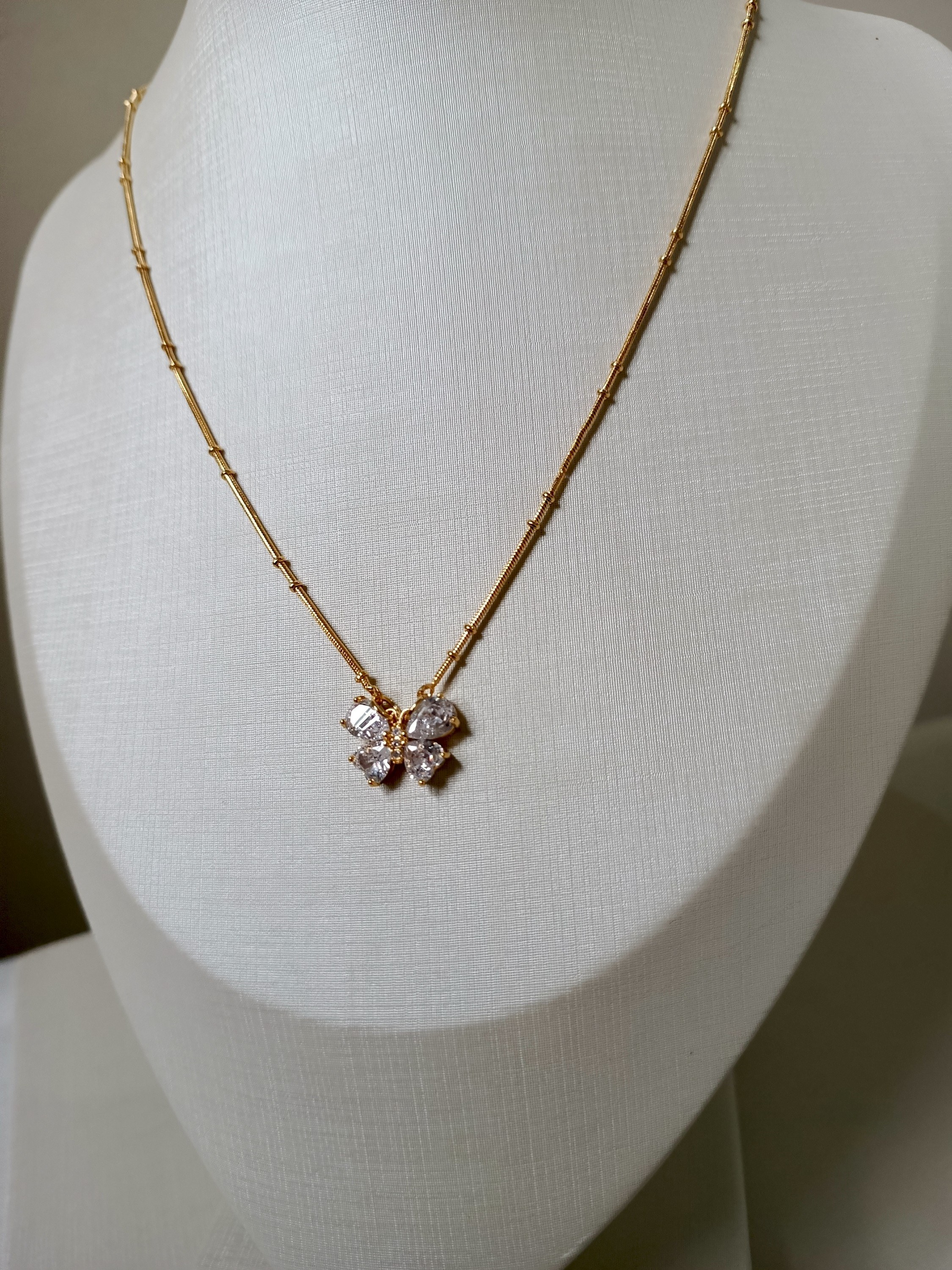 Colar dourado com pingente de borboleta cravejado