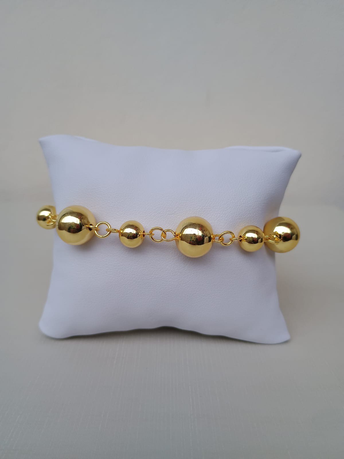 Pulseira dourada com bolinhas pequenas e grandes
