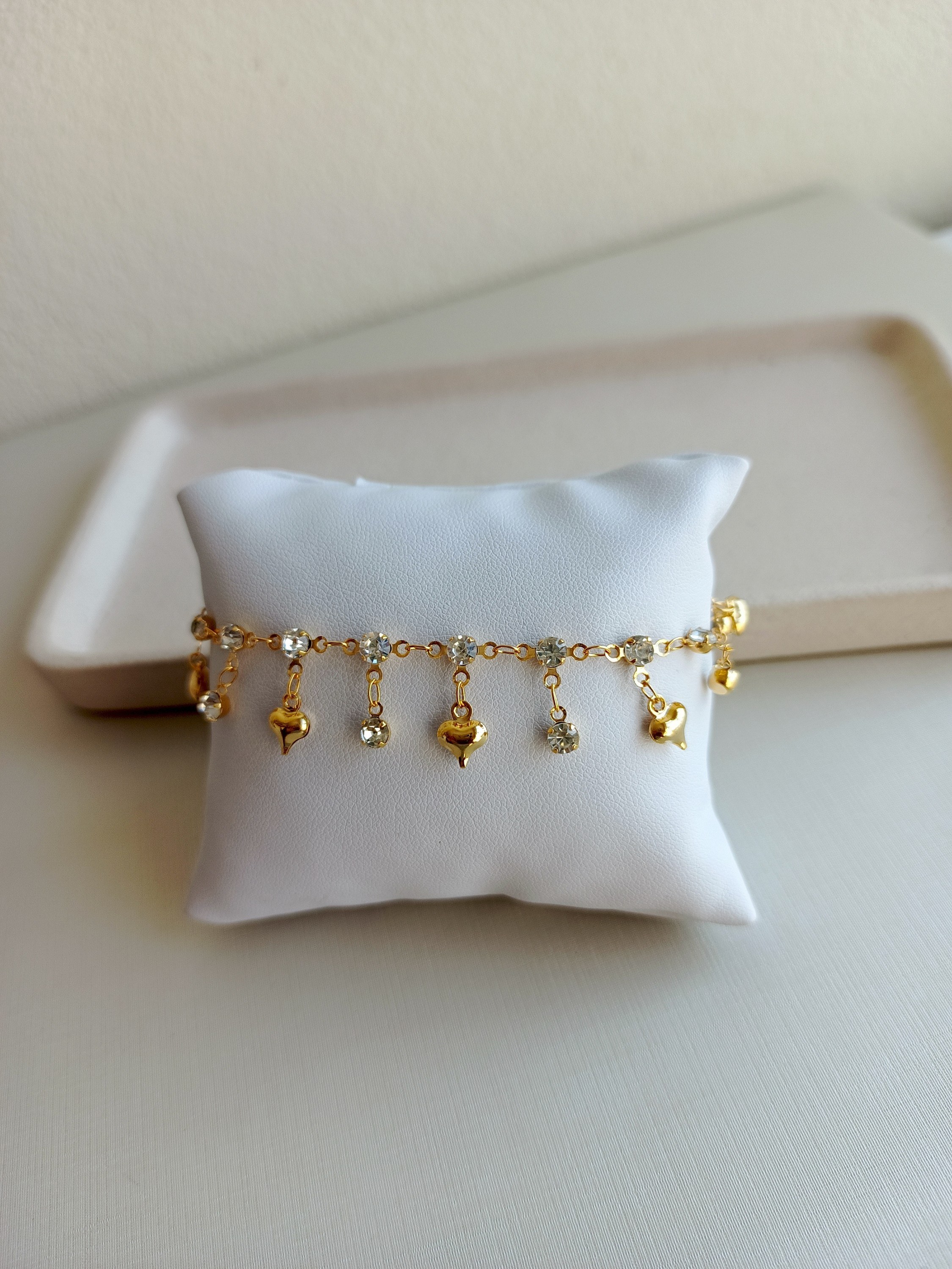 Pulseira dourada com pingente de corações e zircônias